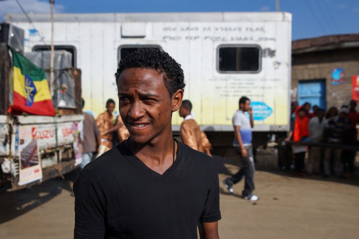 Samson standing in front of a mobile HIV-testing clinic. Photo credit: duckrabbit / International HIV/AIDS Alliance.