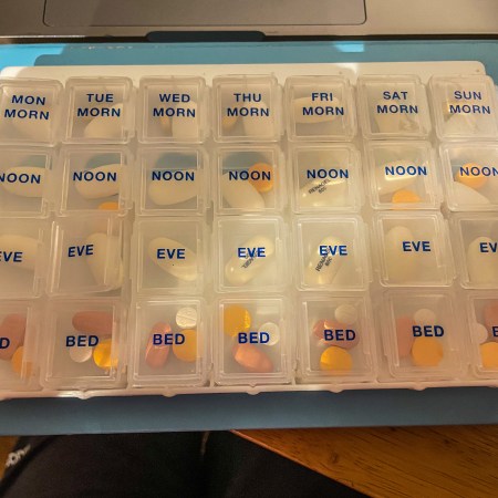 A seven-day pill box with four individual slots for pills each day, filled with medication.