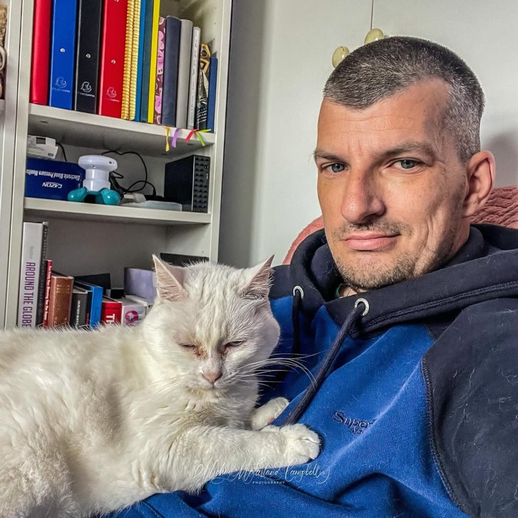 Michael sitting with Scholastica in front of a bookcase.